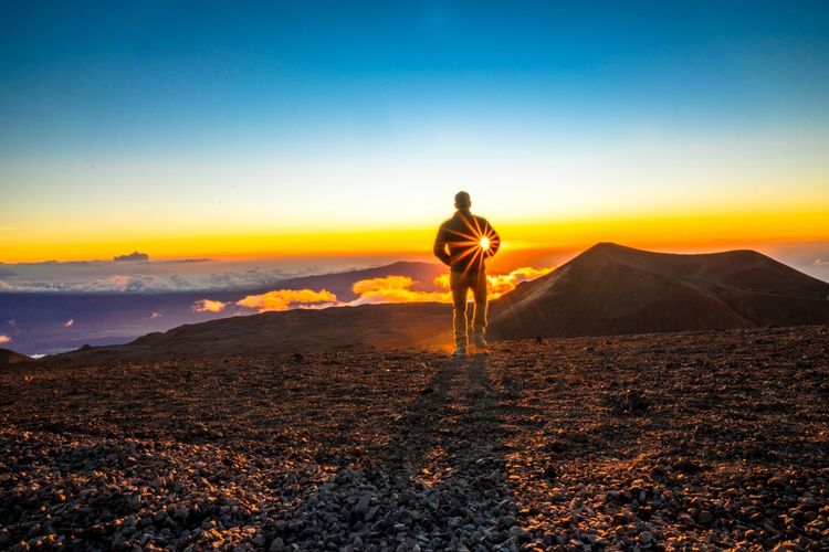 Man standing on land against sky during sunset
