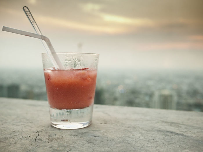 Glass of juice with the view of a city in the background