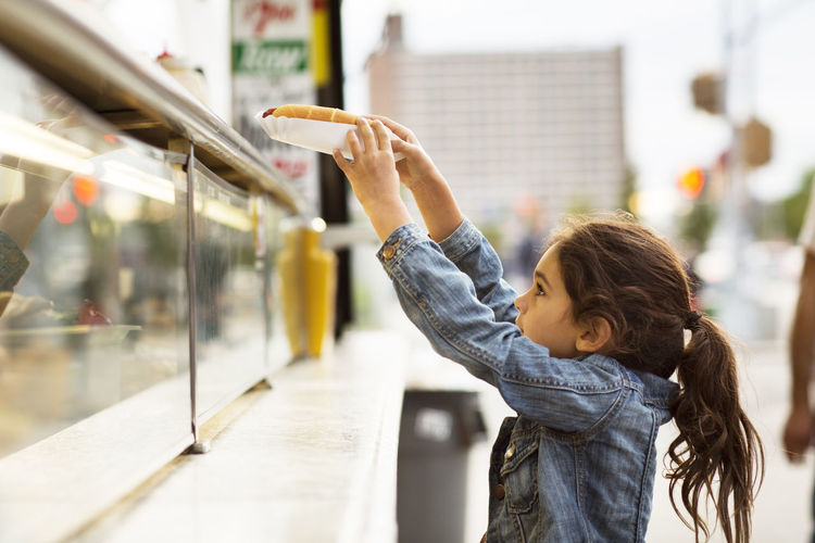 Girl taking hot dog from food truck