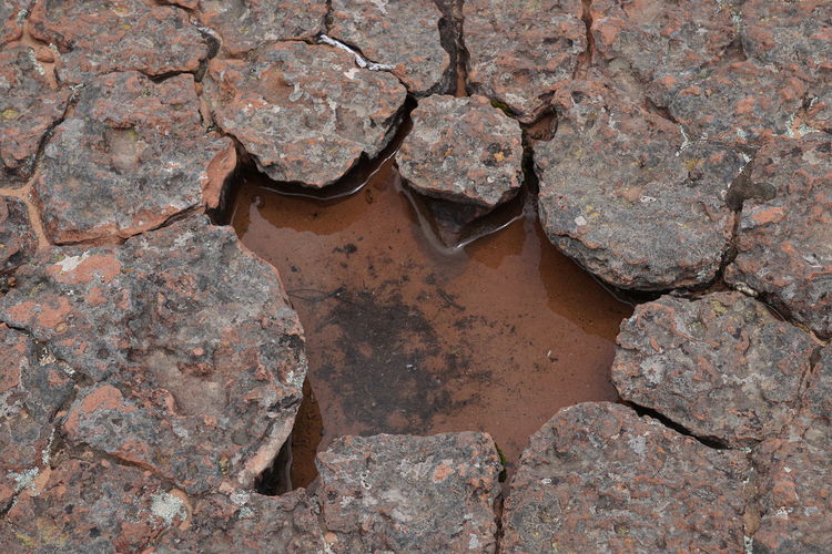 High angle view of puddle on damaged footpath