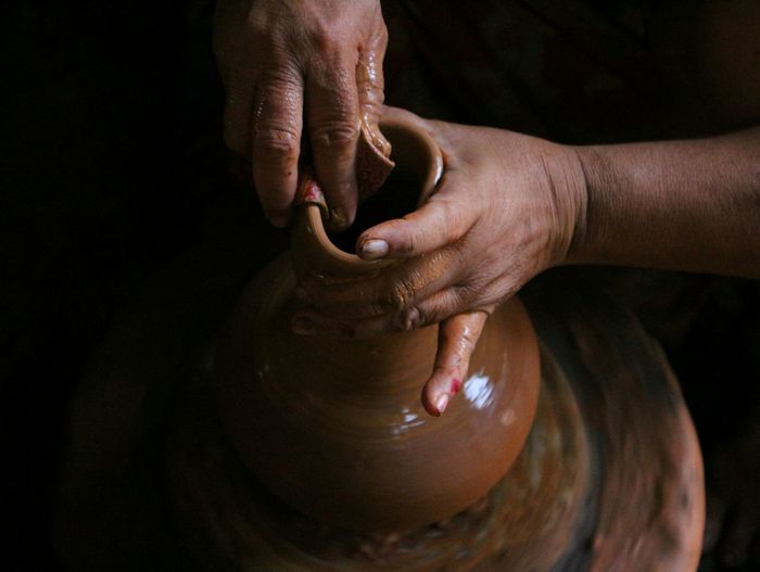 Cropped hands of man molding pot in workshop