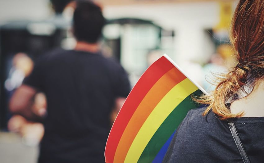 Midsection of woman with rainbow flag in city