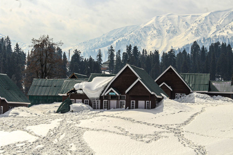 Houses on snow covered land against sky