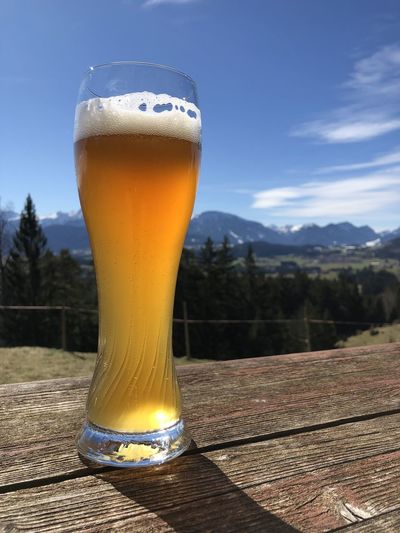 Close-up of beer glass on table against sky