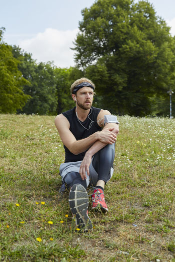 Man listening music while sitting on grassy land in park