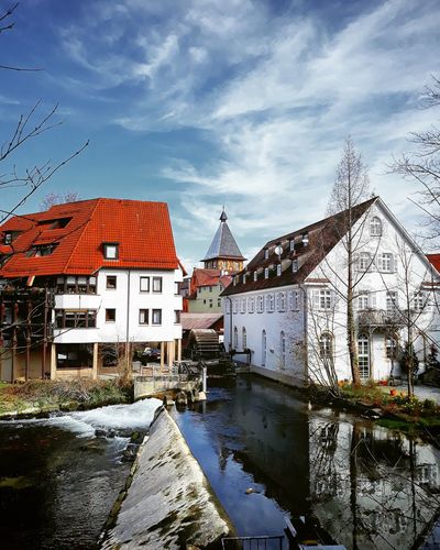 Buildings by river against sky