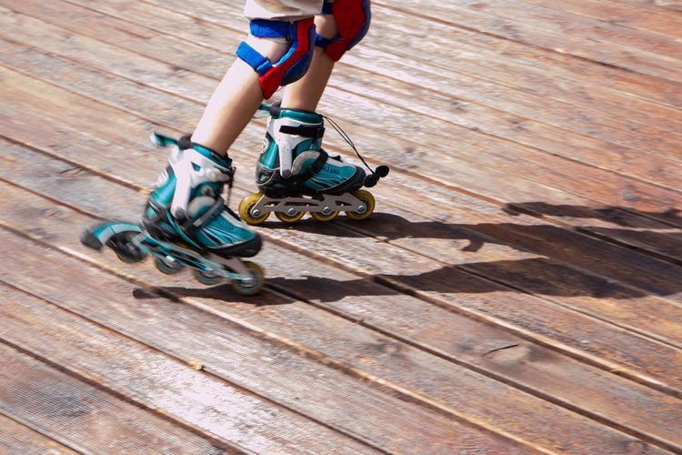 Low section of child on roller skating on floorboard