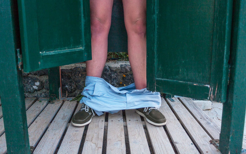 Low section of man with pants down standing on wooden floor