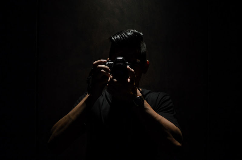 Man photographing against black background