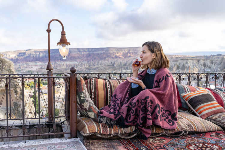 Woman is drinking tea on a balcony in cappadocia, turkey