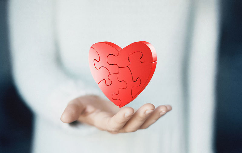 Digital composite image of woman holding heart shape jigsaw puzzle