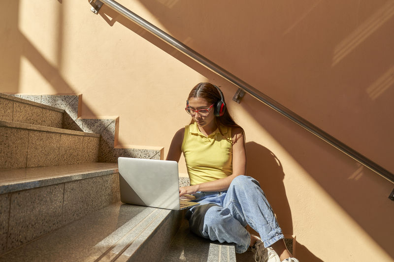 Young female student working with her computer sitting inside buildings