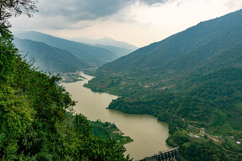 Mountain valley with cloudy sky and river leading at morning from flat angle