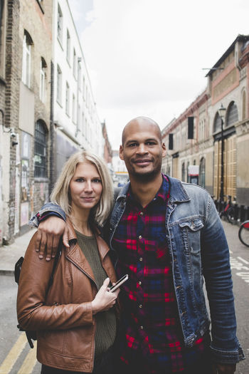 Portrait of smiling young couple standing in city