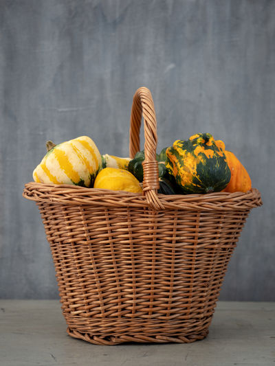 Close-up of fruits in basket on table against wall