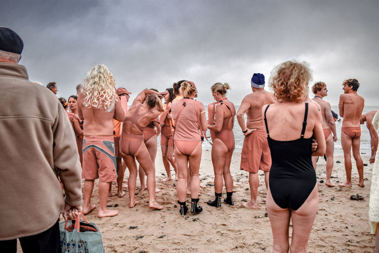 Rear view of people at beach against sky