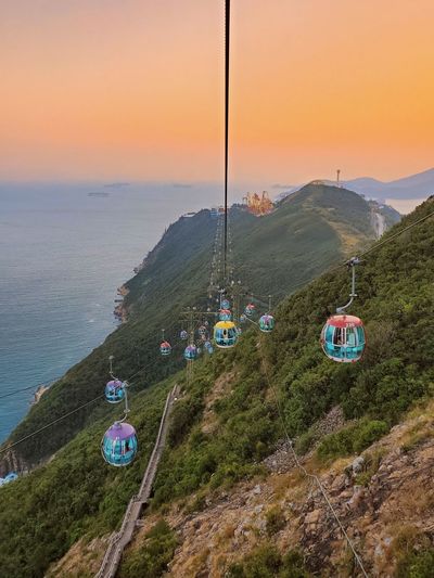 Overhead cable car over sea against sky during sunset