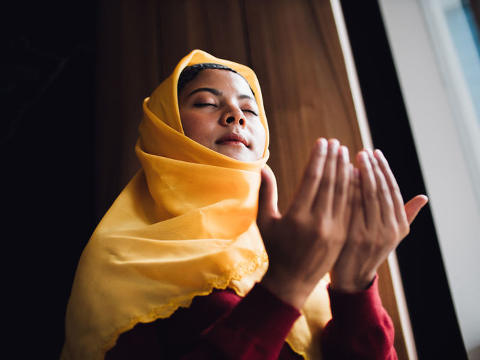 Low angle view of young woman praying