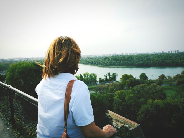 Rear view of woman standing by railing against sky