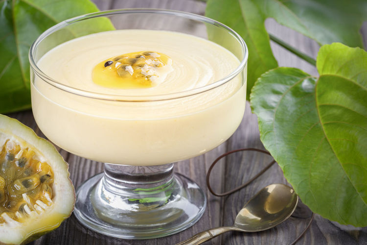 Passion fruit mousse in round glass cup with small spoon