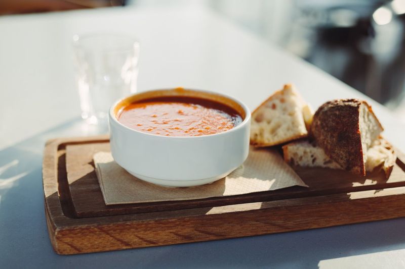 Close-up of soup and bread served on wood at table