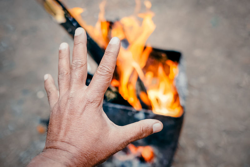 Cropped image of hand against fire
