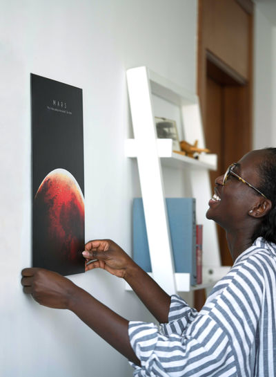 African woman putting poster on the wall