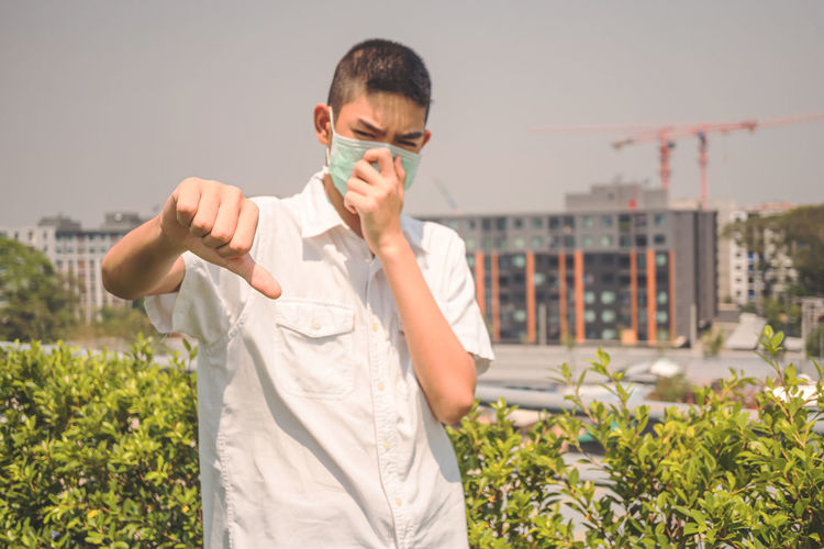 Coronavirus covid-19 and the pm2.5 air pollution concept.asian young boy in a medical mask sneezing.