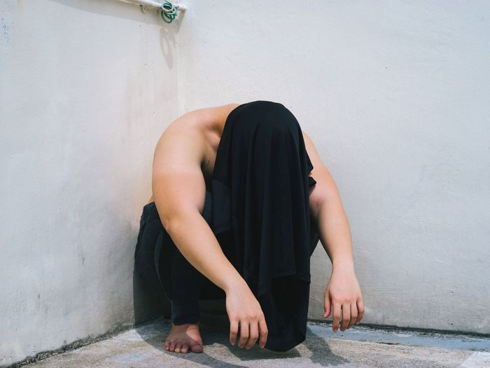 View of crouching man with shirt over head