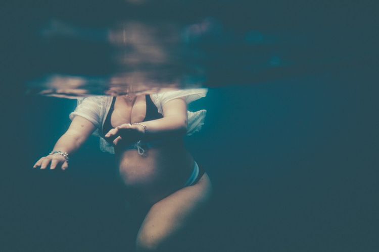 Midsection of pregnant woman swimming in pool