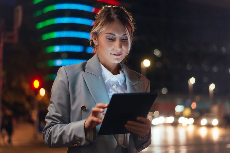 Portrait of businessman using digital tablet at night