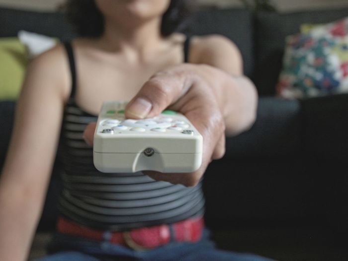 Midsection of woman using remote control