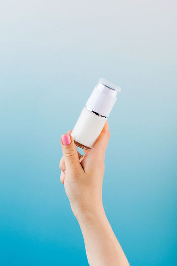 A mock-up of a jar of moisturizer in a woman's hand on a blue background.