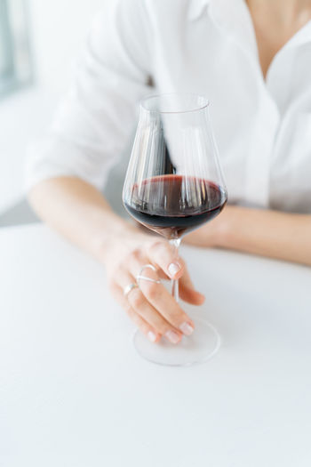 Midsection of woman holding wineglass on table