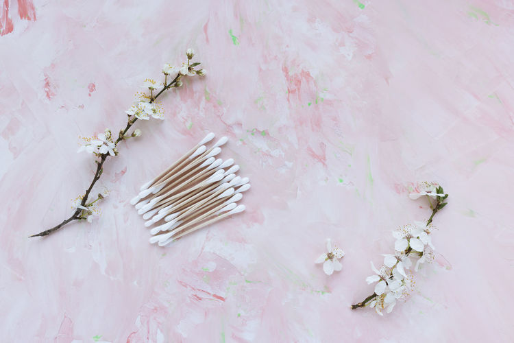 Eco-friendly bamboo cotton buds on pink, white spring flowers. cotton swabs, ear cleaner