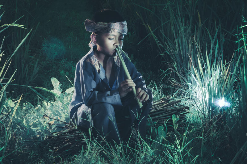 Young woman sitting on field at night