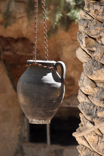 Old clay pot hanging by tree on sunny day