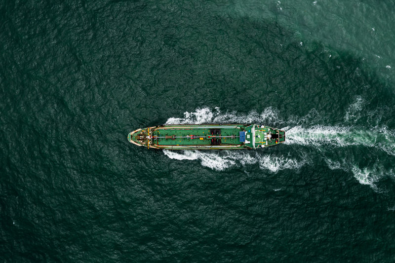 Aerial top view oil ship tanker sailing full speed with wave and splash water 