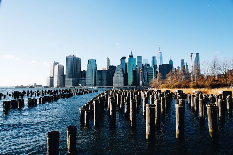 Wooden posts in sea against clear sky