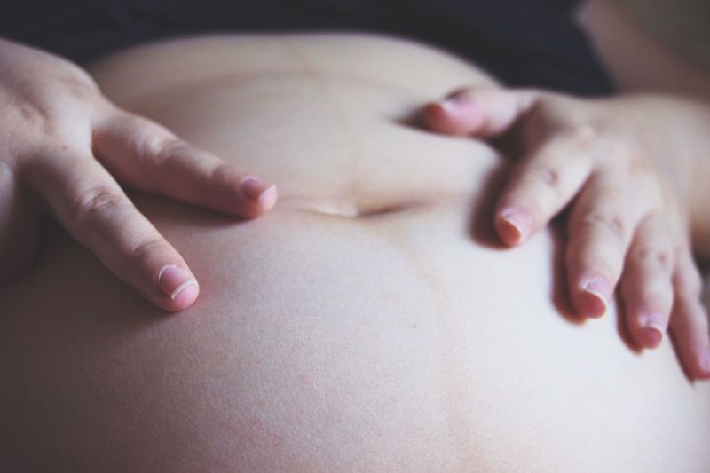 Midsection of pregnant woman gesturing on stomach