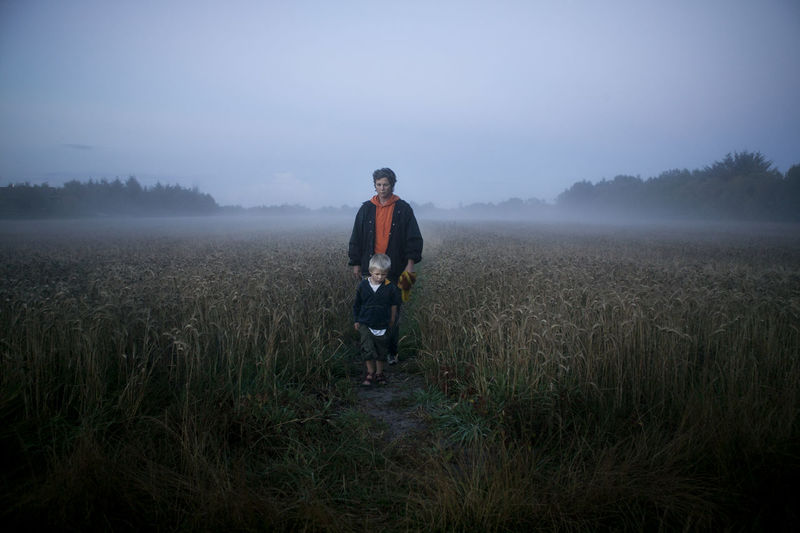 Mother walking with son through foggy meadow