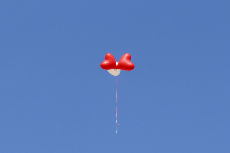 Three helium balloons flying against clear sky
