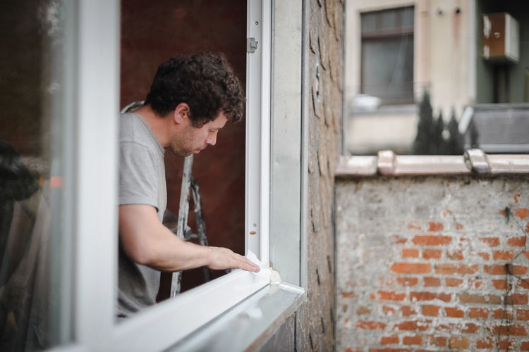 Side view of man looking through window