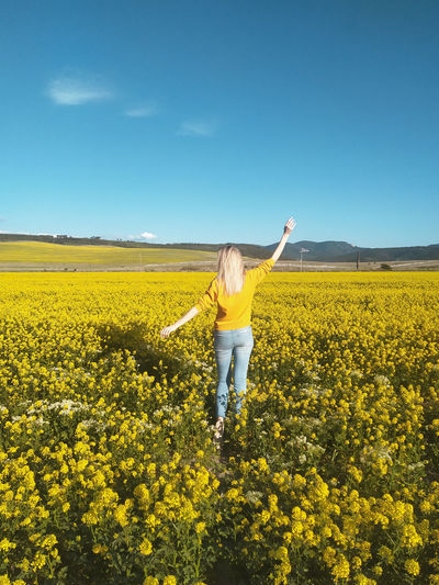 Person standing by yellow flowers on field