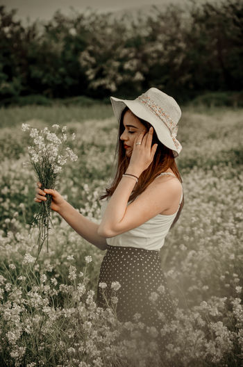 Woman wearing hat standing on field