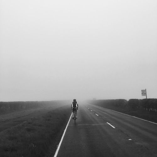 Rear view of man bicycling on country road