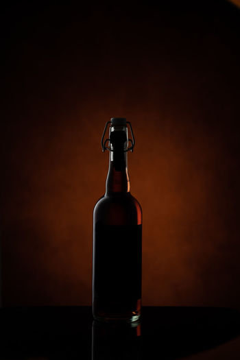 Close-up of glass bottle on table against black background