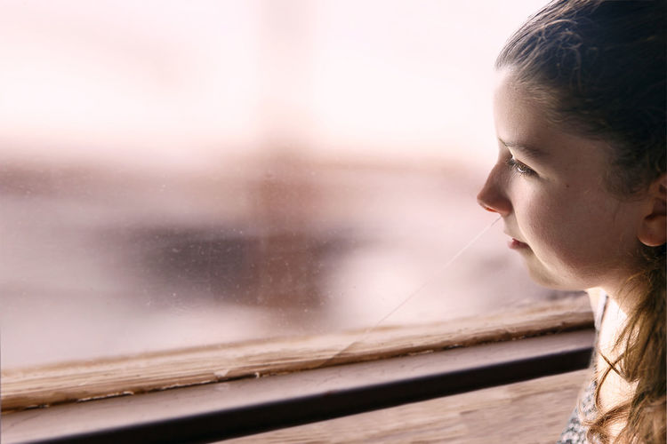 Close-up of teenage girl looking through window