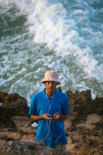 Front view of man standing at the beach holding a mobile phone