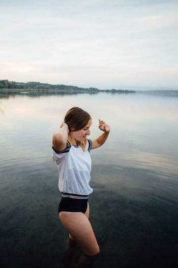 Woman standing in lake against sky